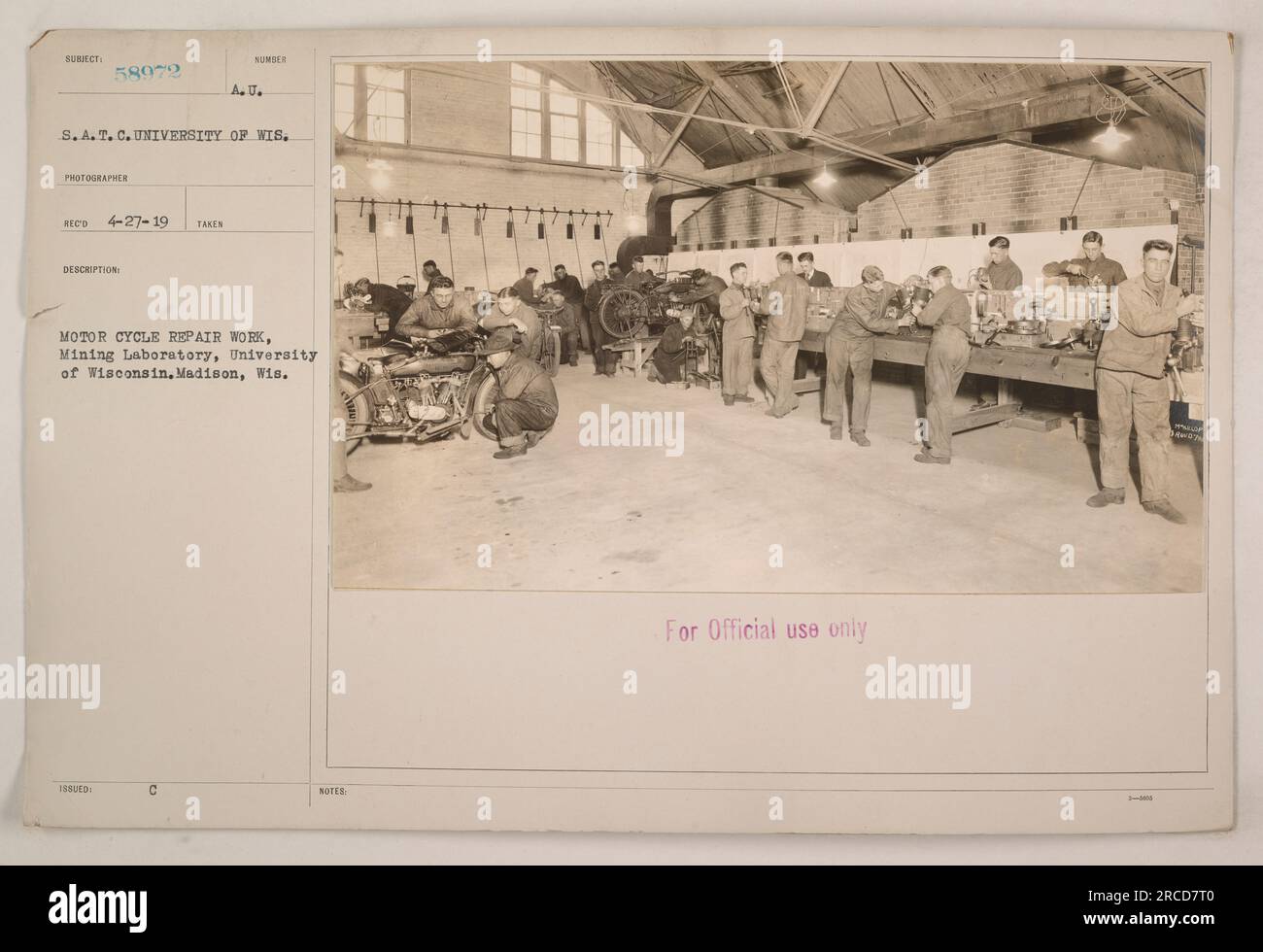 A motor cycle being repaired in the Mining Laboratory at the University of Wisconsin, Madison. This photograph was taken by photographer S.A.T. C. in 1919. The image shows a maintenance operation being conducted for official use only. Image available at: https://www.aaa.si.edu/collections/items/detail/american-university-reel-4-record-31913. Please note that the photographer's name is abbreviated to S.A.T. C. and the city's name is abbreviated to Wis. C. for brevity. Stock Photo