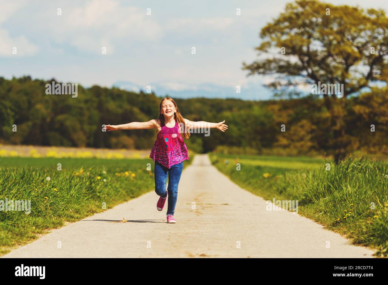 Kid girl running down the road in countryside on a very hot day, image