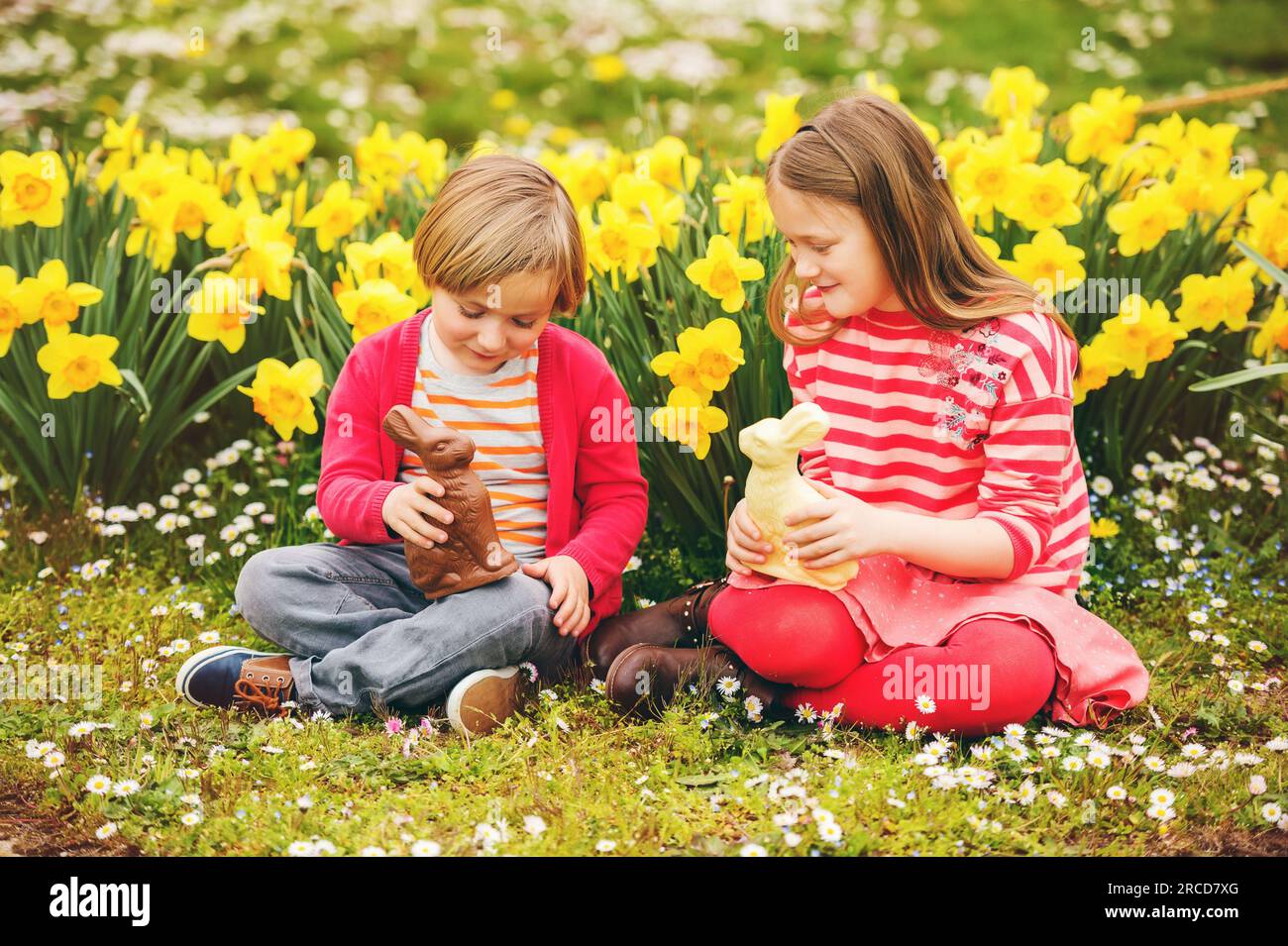 Cute little kids, big sister and small brother, with chocolate Easter bunnies celebrating traditional feast. Family, holiday, spring , carefree childh Stock Photo