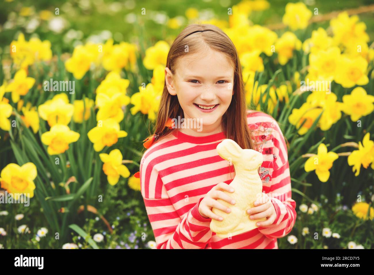 Cute little kid girl with white chocolate Easter bunny celebrating traditional feast. Family, holiday, spring , carefree childhood concept. Stock Photo