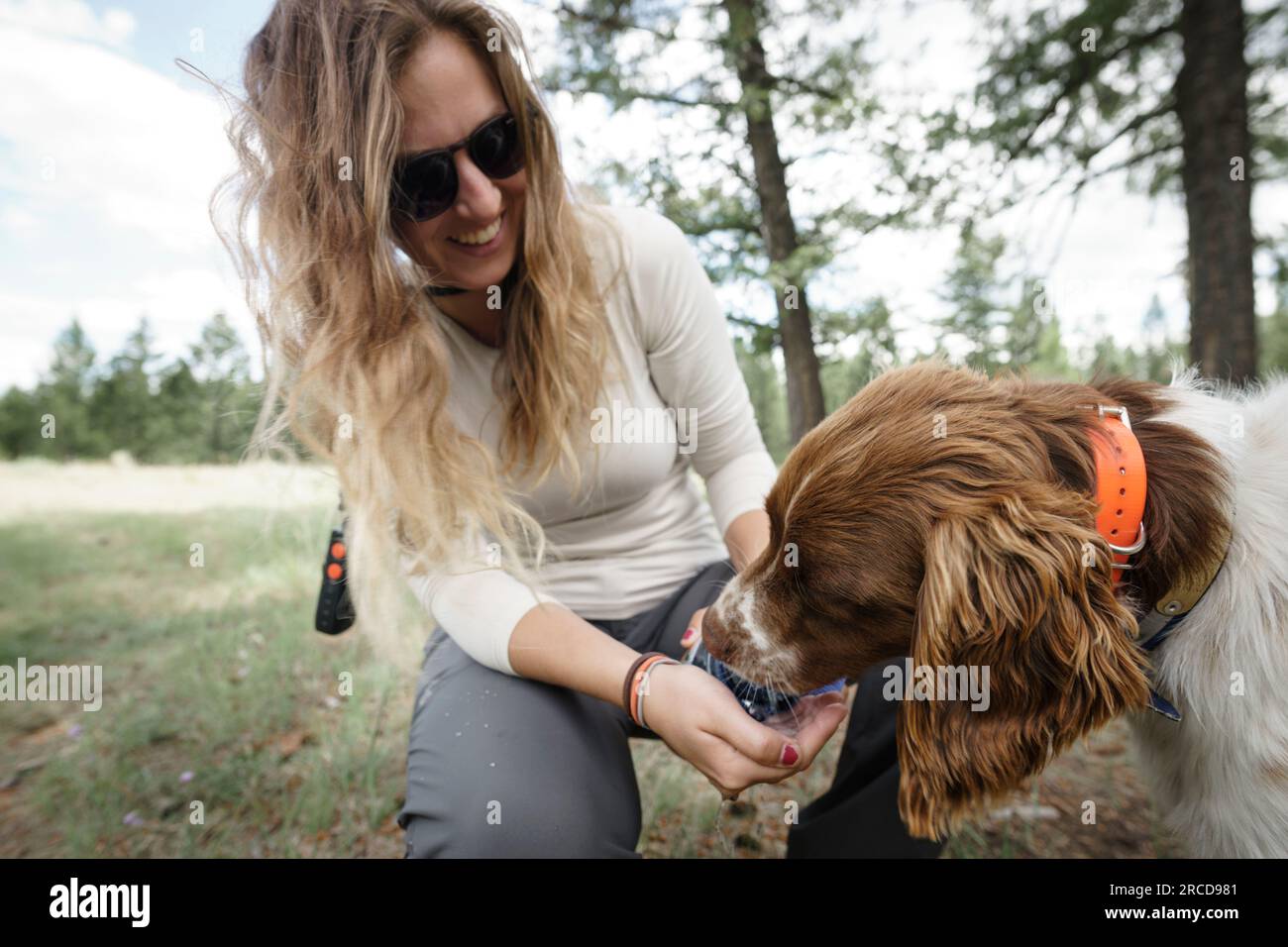 Closeup of young women smiling feeding dog water from hand, BC, Canada Stock Photo