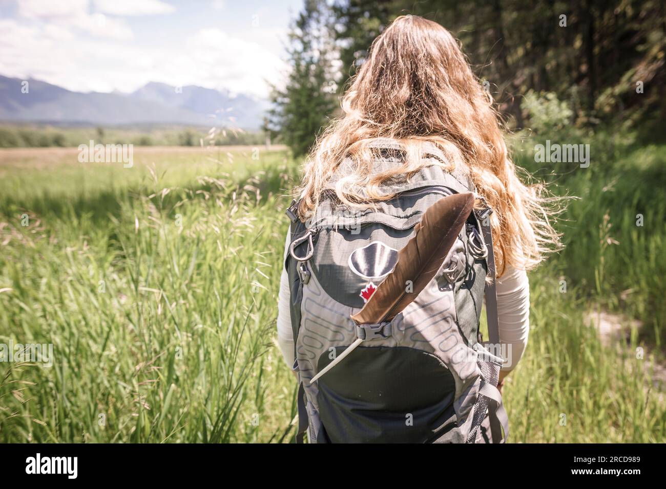 Women with blonde hair and backpack with feather hiking in Canada Stock Photo