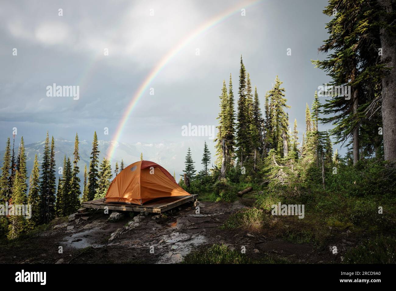 Camping tent in mountain forest with rainbow, British Columbia, Canada Stock Photo