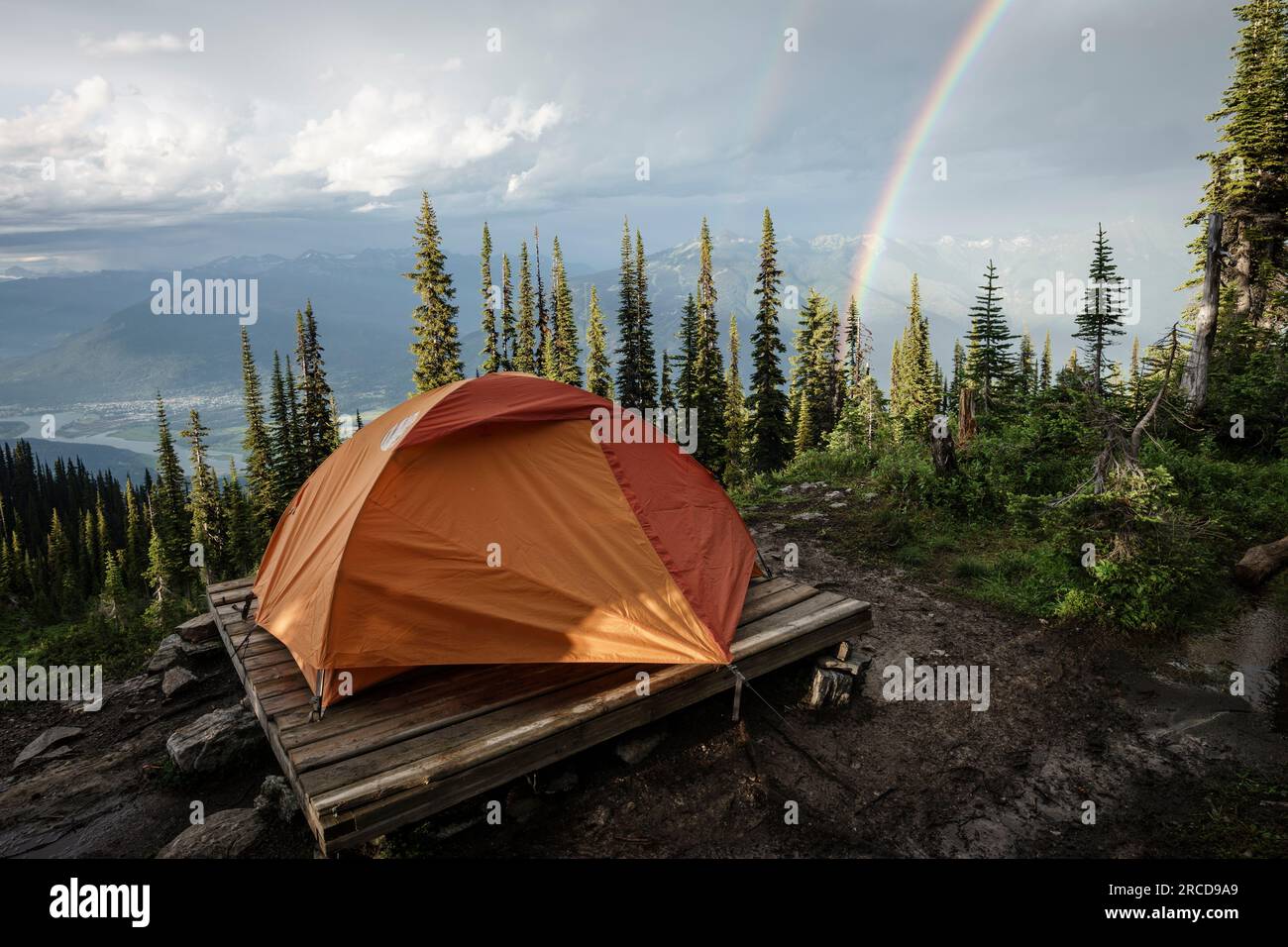 Camping tent in mountain forest by rainbow with town below, BC, Canada Stock Photo Alamy