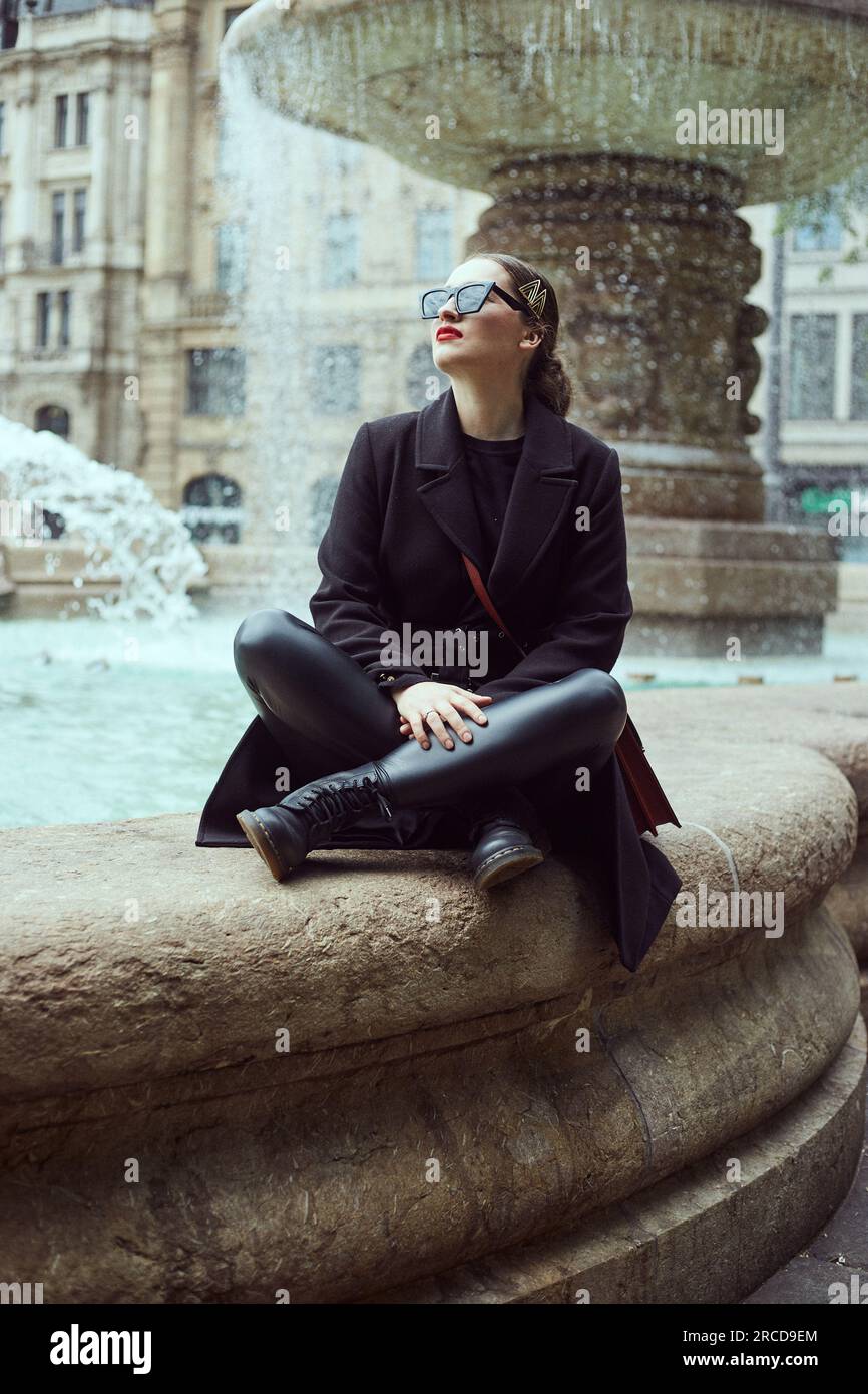Young woman sitting wall hi-res stock photography and images - Alamy