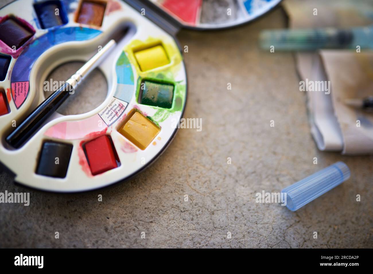 Box of watercolors and brushes on a table. Stock Photo