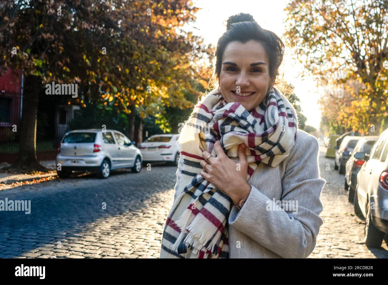 Portrait of smiling young woman with scarf standing on the street Stock Photo