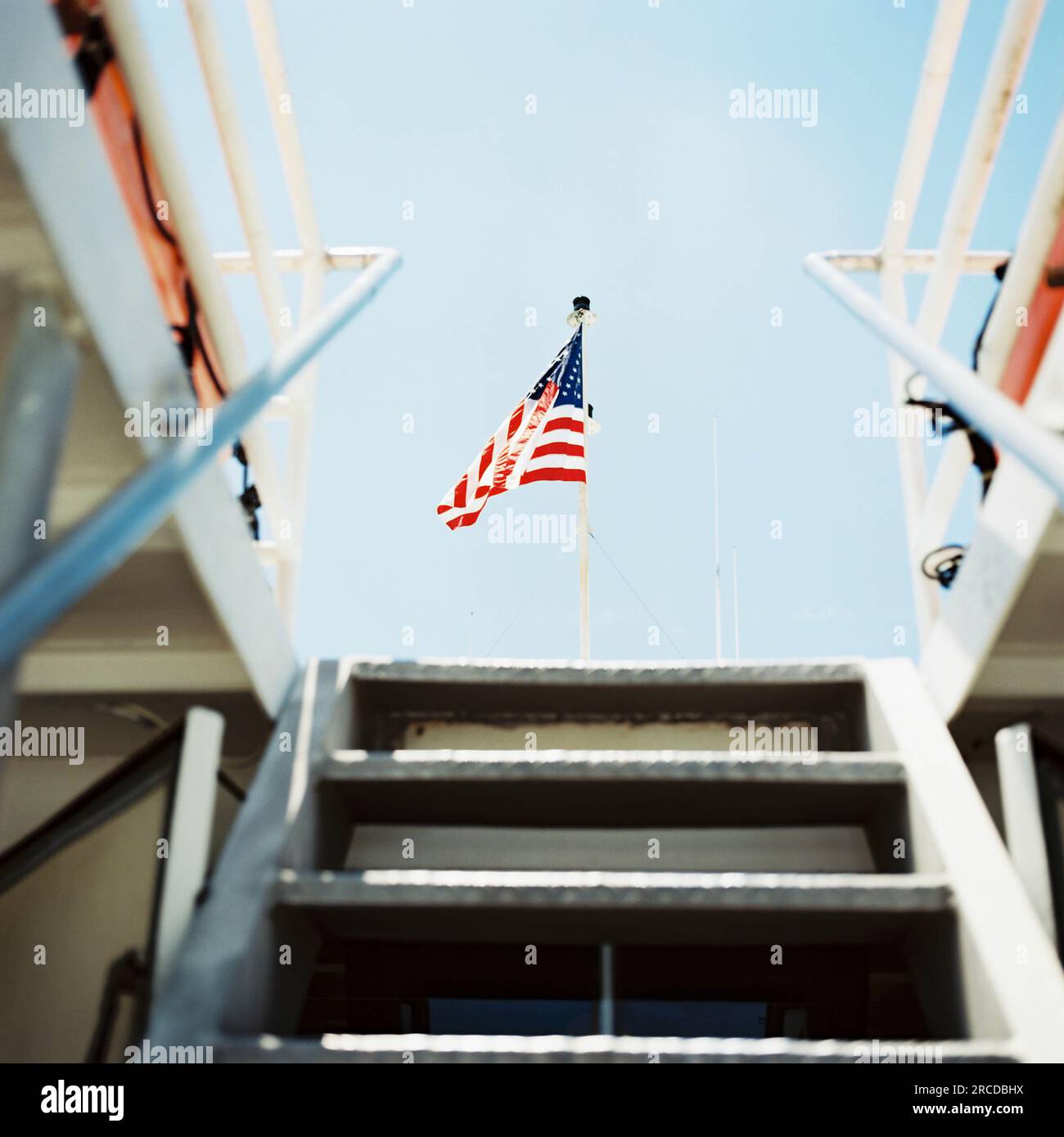 View from below deck on a boat, looking up stairs at an American flag Stock Photo