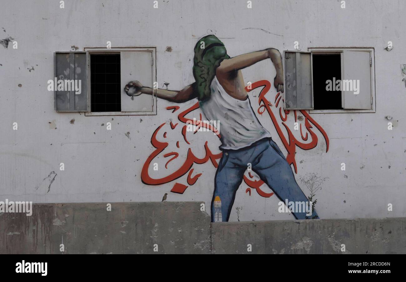 A painted wall depicting a Palestinian rioter sits on display at a ...
