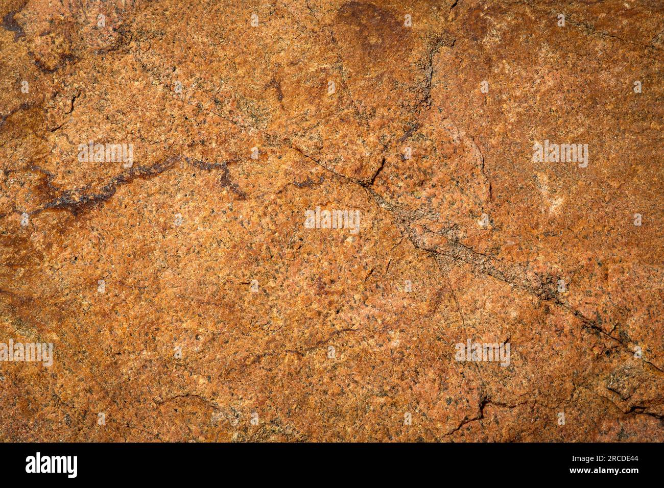 Old orange stonewall in closeup with cracks Stock Photo