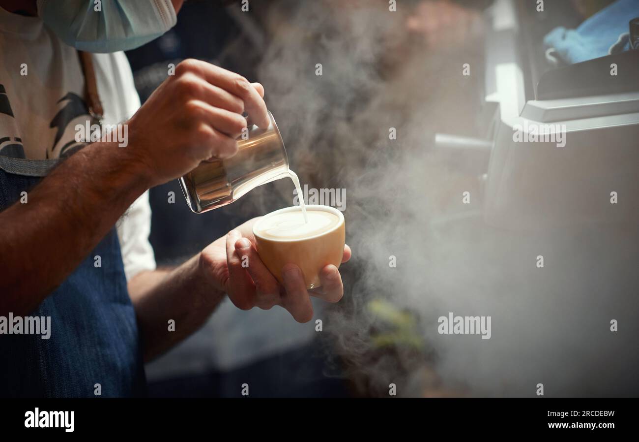 Caucasian man pouring milk in a coffee Stock Photo
