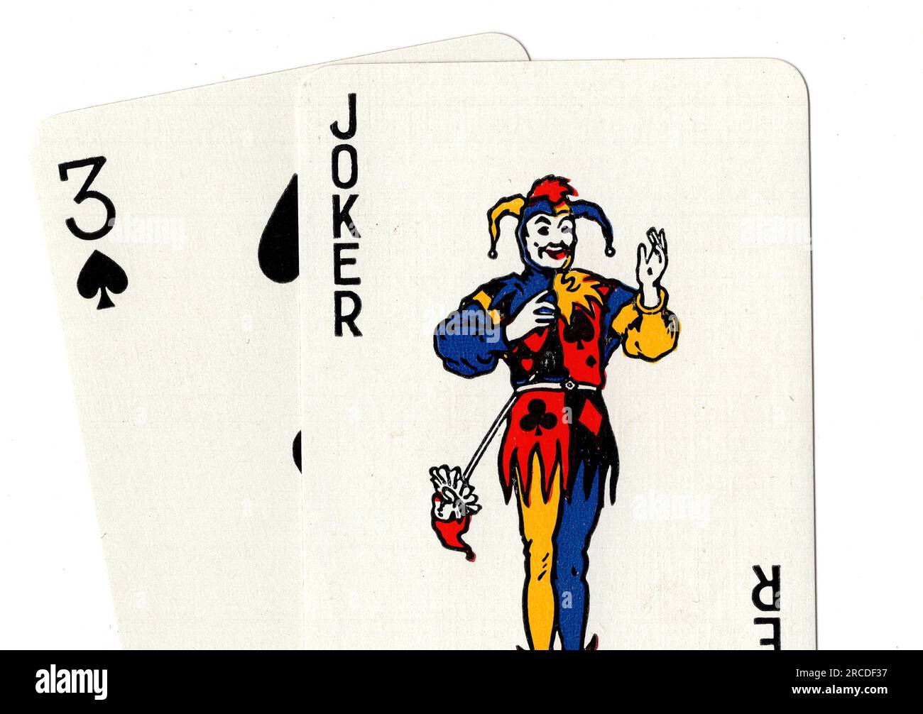 Vintage playing cards showing a joker and a three of spades on a white