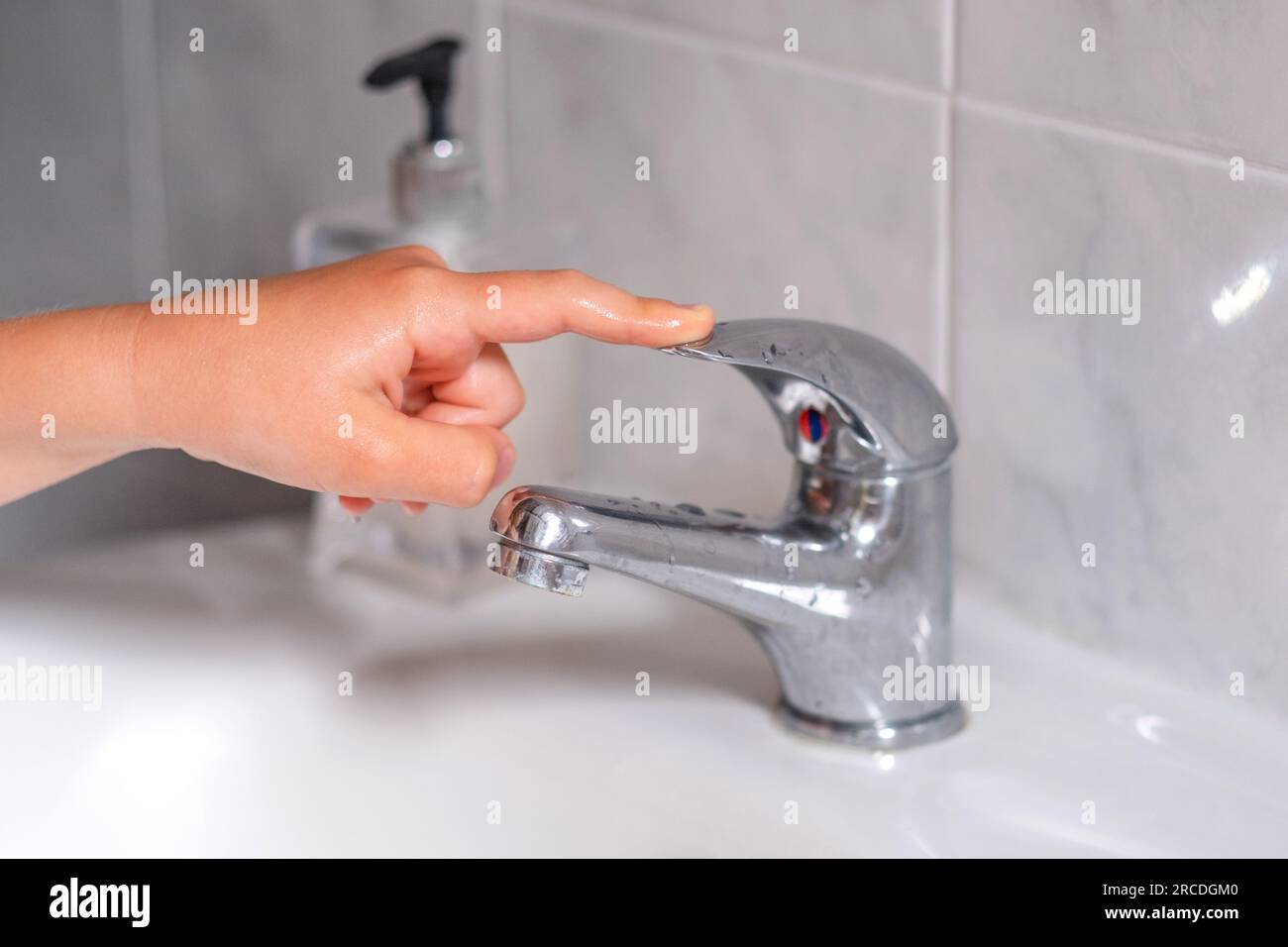 The child turn off the water tap after hygienic procedures. The concept save water and protect the environment. Stock Photo