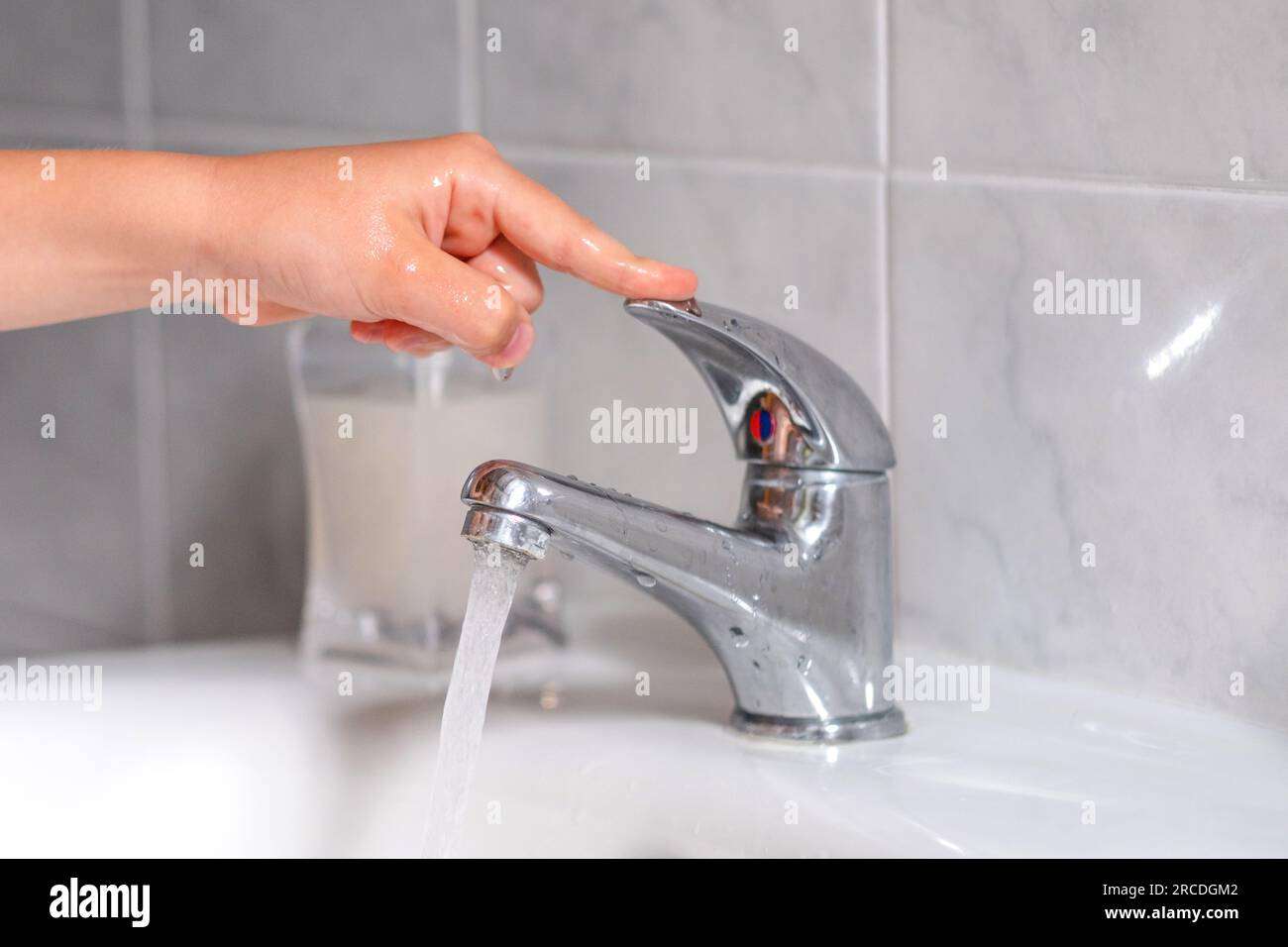 The faucet in the bathroom with running water. The child fix water leake. The concept save water and protect the environment. Stock Photo