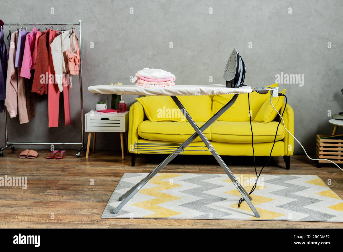 housekeeping concept, stack of folded and clean clothes near iron on