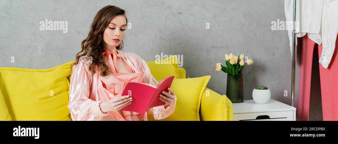 concept photography, woman with brunette wavy hair, domestic life, attractive housewife reading book, sitting on yellow couch, comfortable living, dom Stock Photo