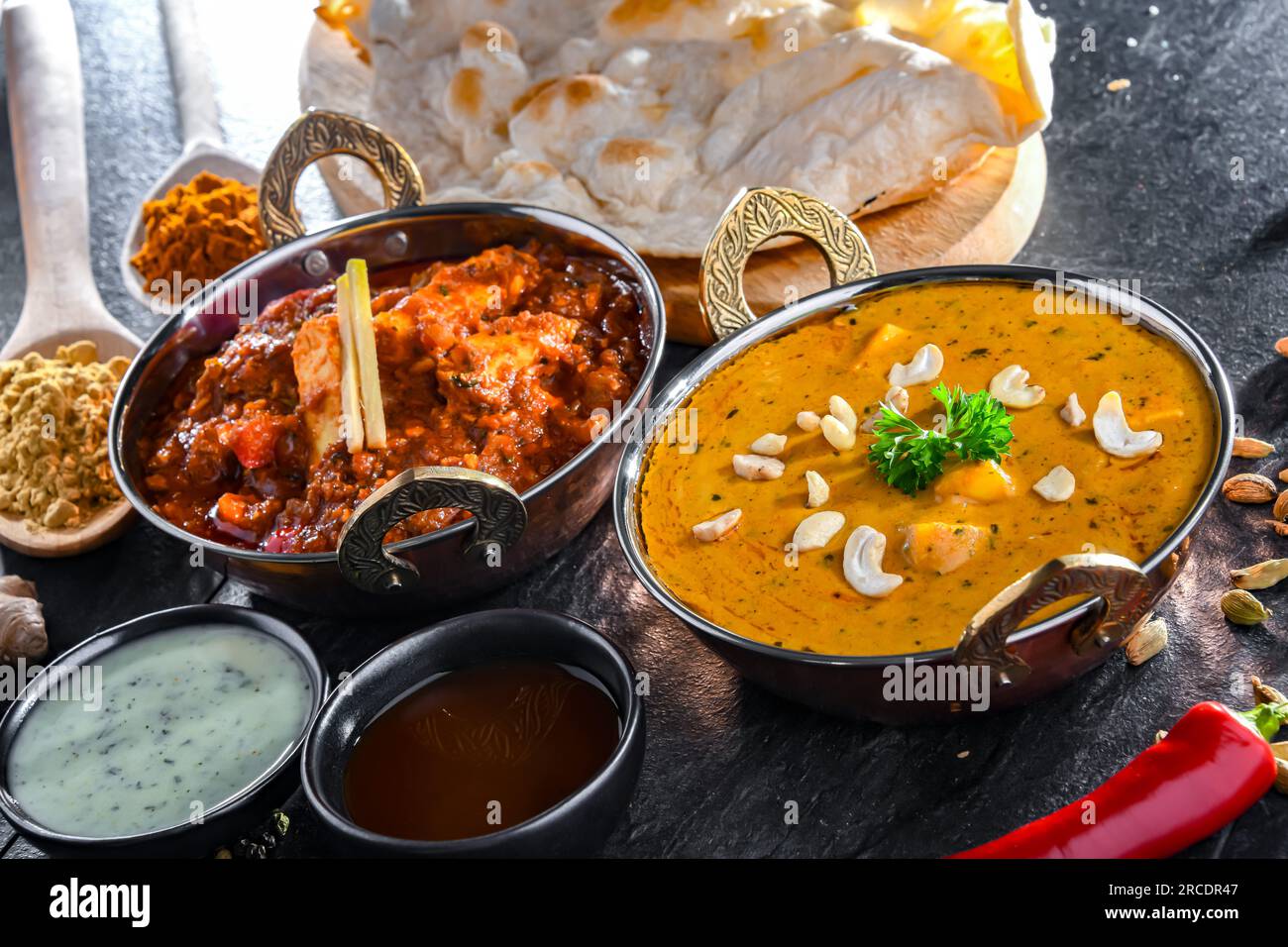 Composition with indian dishes: madras paneer, palak paneer and shahi paneer with basmati rice served in original indian karahi pots. Stock Photo