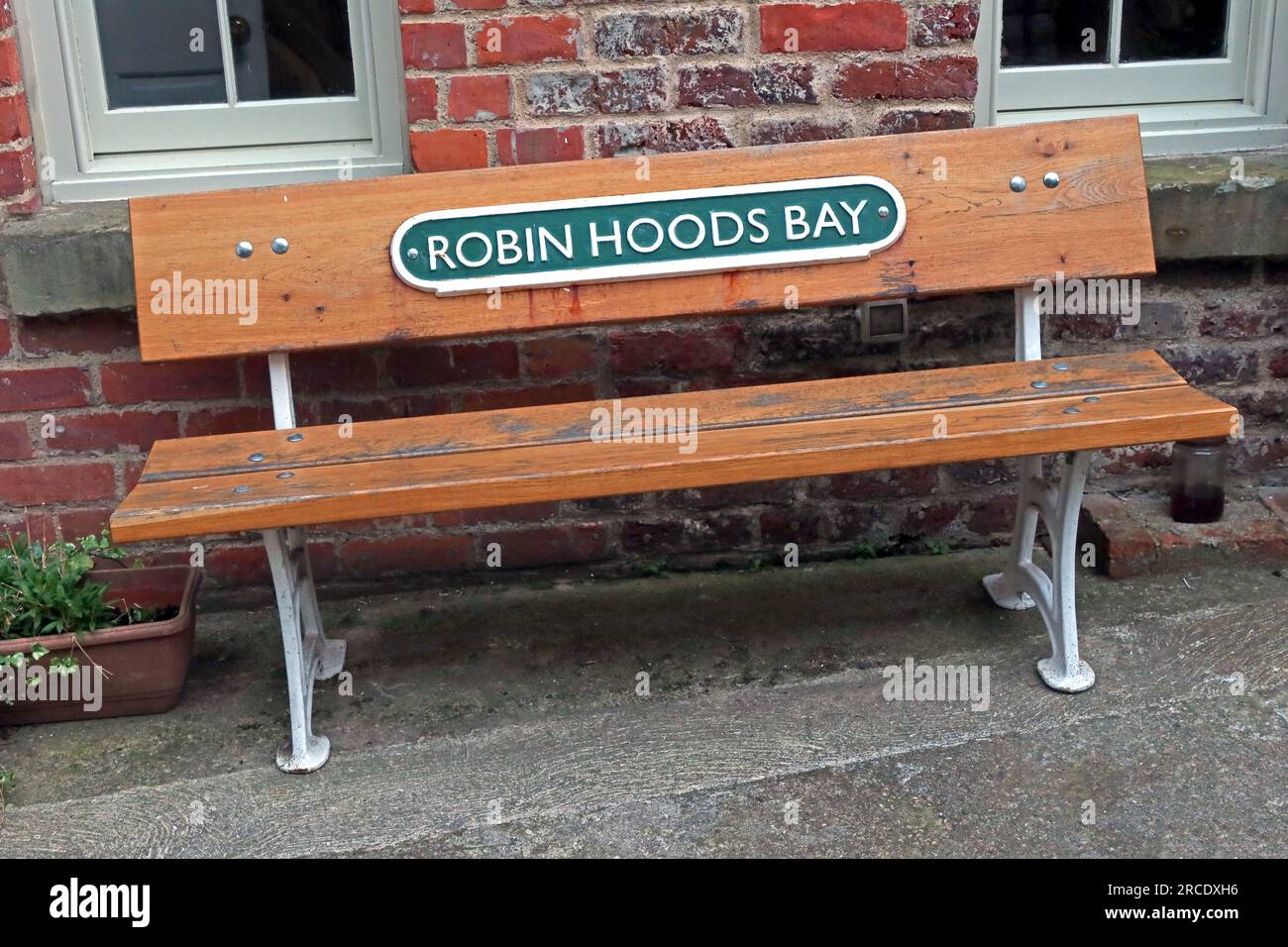 Bench at Robin Hoods Bay, with old cast iron railway station sign, near Whitby, North Yorkshire, England, UK, YO22 4SE Stock Photo