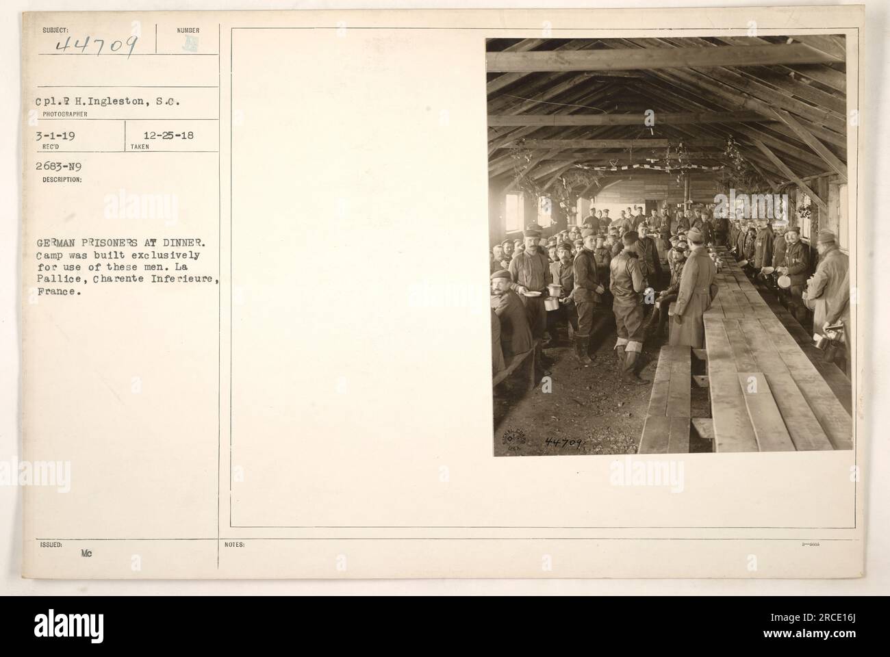 American soldiers, led by Corporal H. Ingleston, are seen dining with German prisoners at a specially constructed camp in La Pallice, France. The photograph was taken on March 1, 1919. The camp, intended exclusively for the captured German soldiers, served as a temporary residence for them. Stock Photo