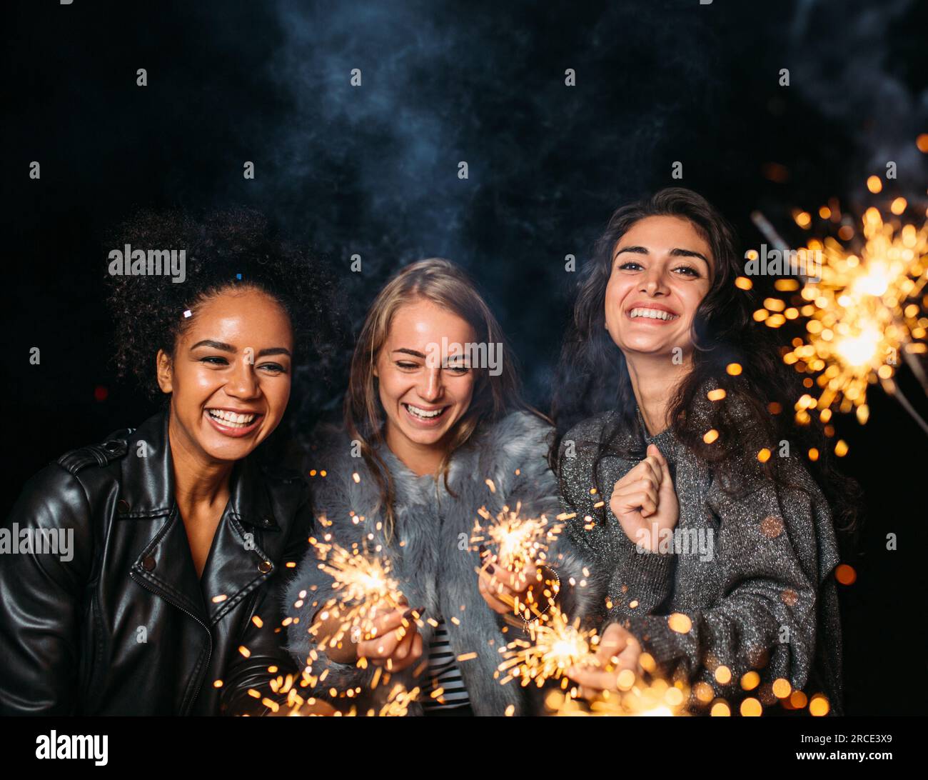 Three young women laughing at night and holding sparklers Stock Photo ...