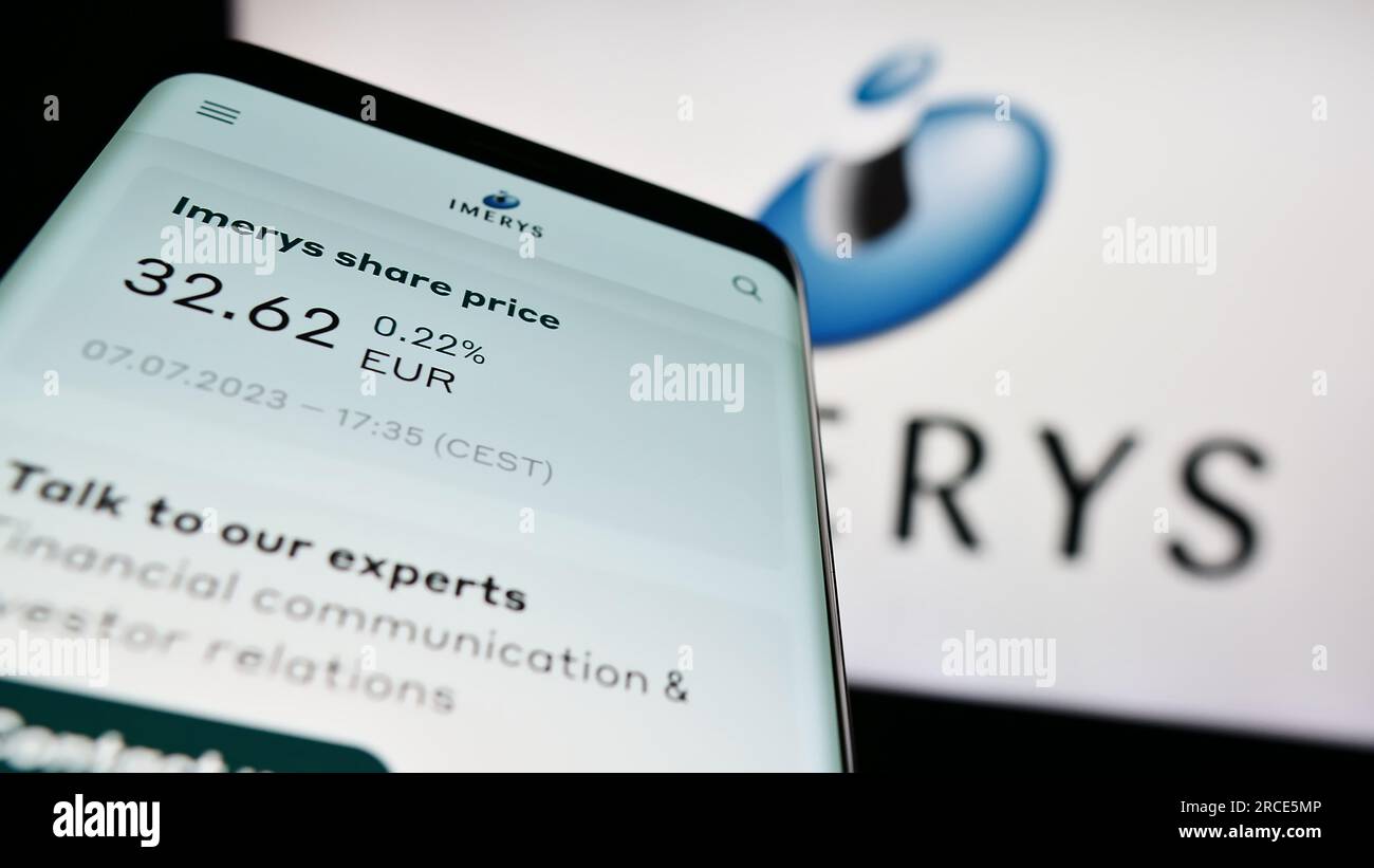 Mobile phone with webpage of French mining company Imerys S.A. on screen in front of business logo. Focus on top-left of phone display. Stock Photo