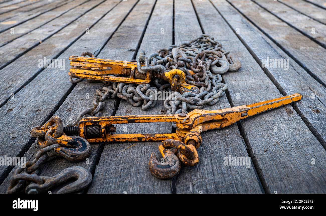 Two old, used and rusty tie down chains and binders, used to secure an object in place on a
