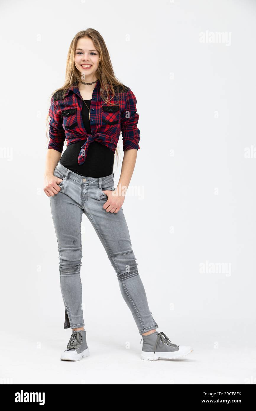 A confident girl stands with her hands tucked in the pockets of her pants. Stock Photo