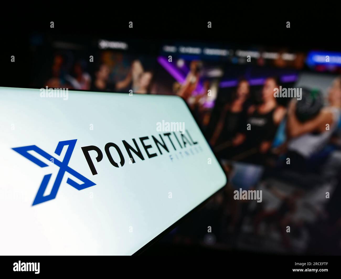 Smartphone with logo of American franchise company Xponential Fitness Inc. on screen in front of website. Focus on center-left of phone display. Stock Photo