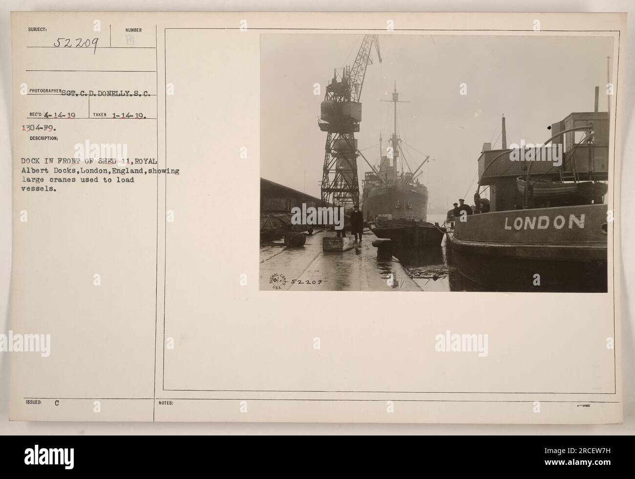Dock at Royal Albert Docks, London, England, showing cranes used for loading vessels. Panel labels indicate the details of the photograph, including the subject, photographer, date, and description. This image is part of the collection 'Photographs of American Military Activities during World War One.' Stock Photo