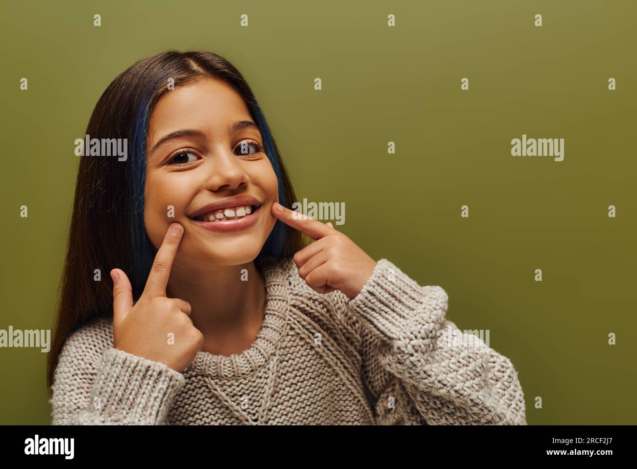 Portrait of cheerful preteen kid with dyed hair wearing modern knitted