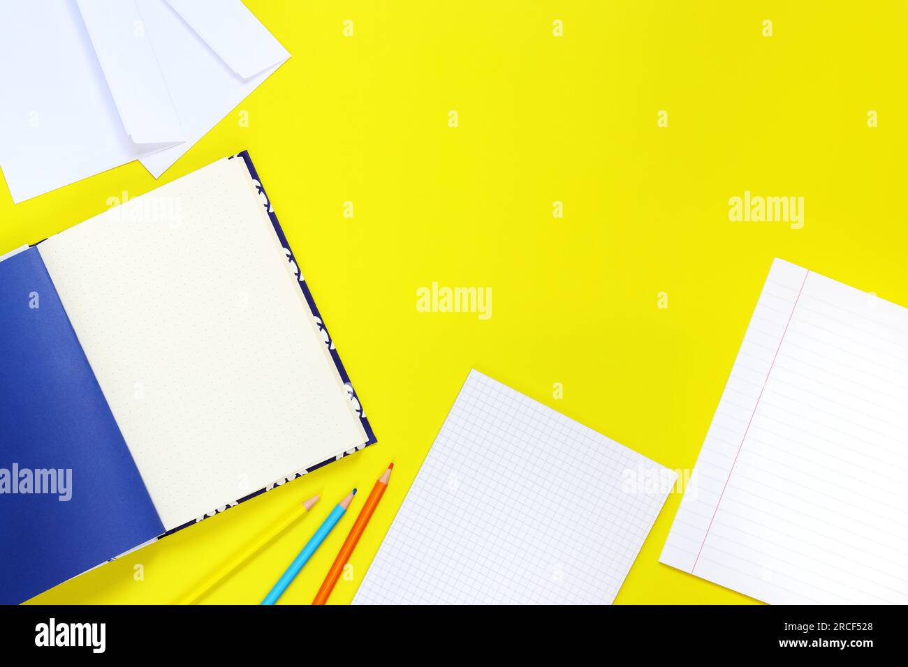 Back to school. Workspace, top view, flat lay. Open notebooks, pencils and envelopes on a yellow background. Mock-up notebooks and a set of stationery Stock Photo