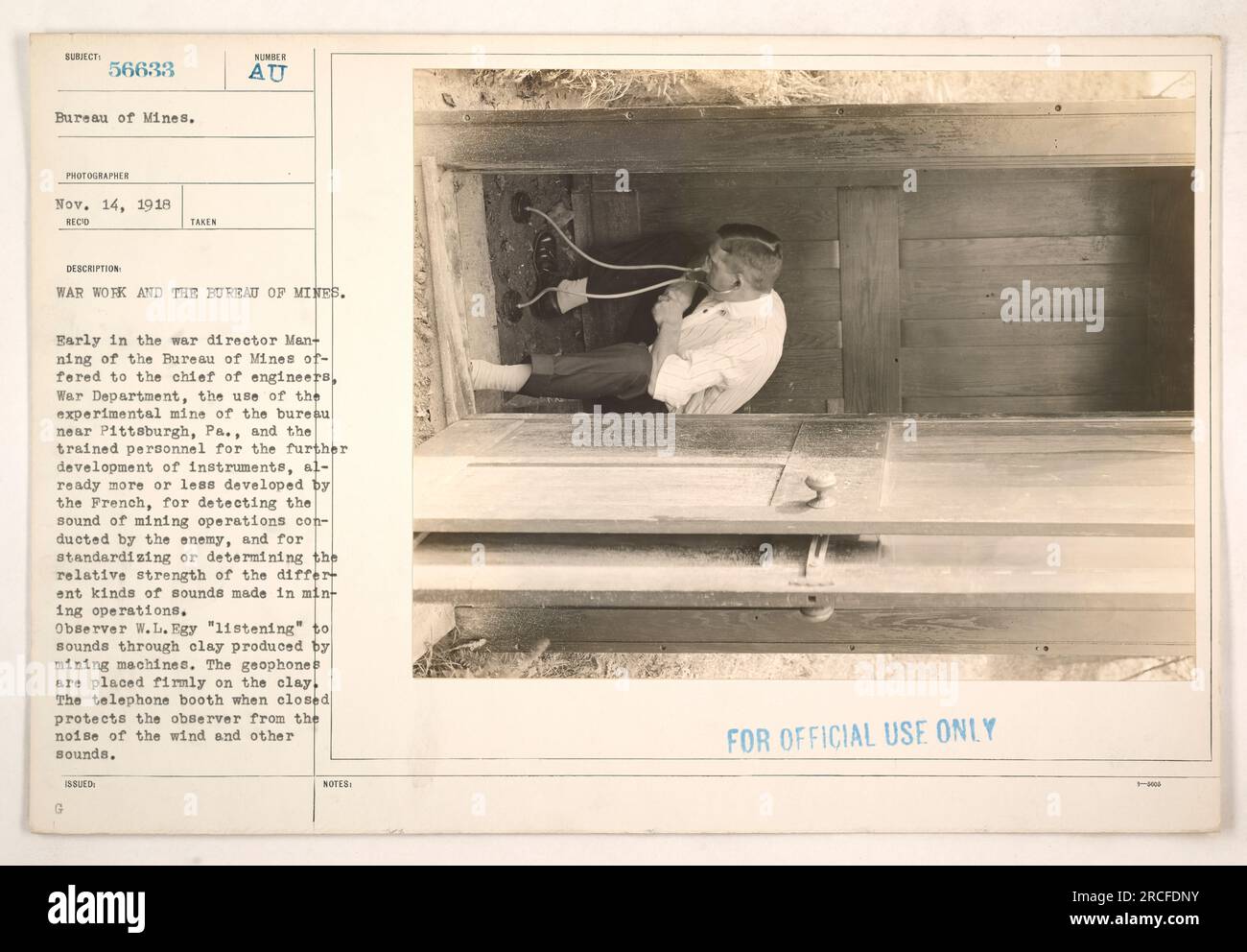 Observer W.L. Egy using geophones to detect sounds produced by mining machines. He listens to the sounds through clay, with the geophones placed firmly on the clay. A closed telephone booth protects the observer from external noises like wind. This technology was developed by the Bureau of Mines for detecting enemy mining operations during World War I. Stock Photo