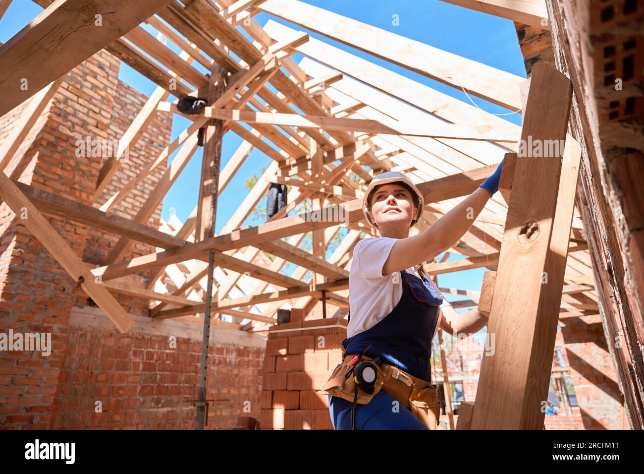 Confident forewoman standing at ladder and evaluating building stage Stock Photo