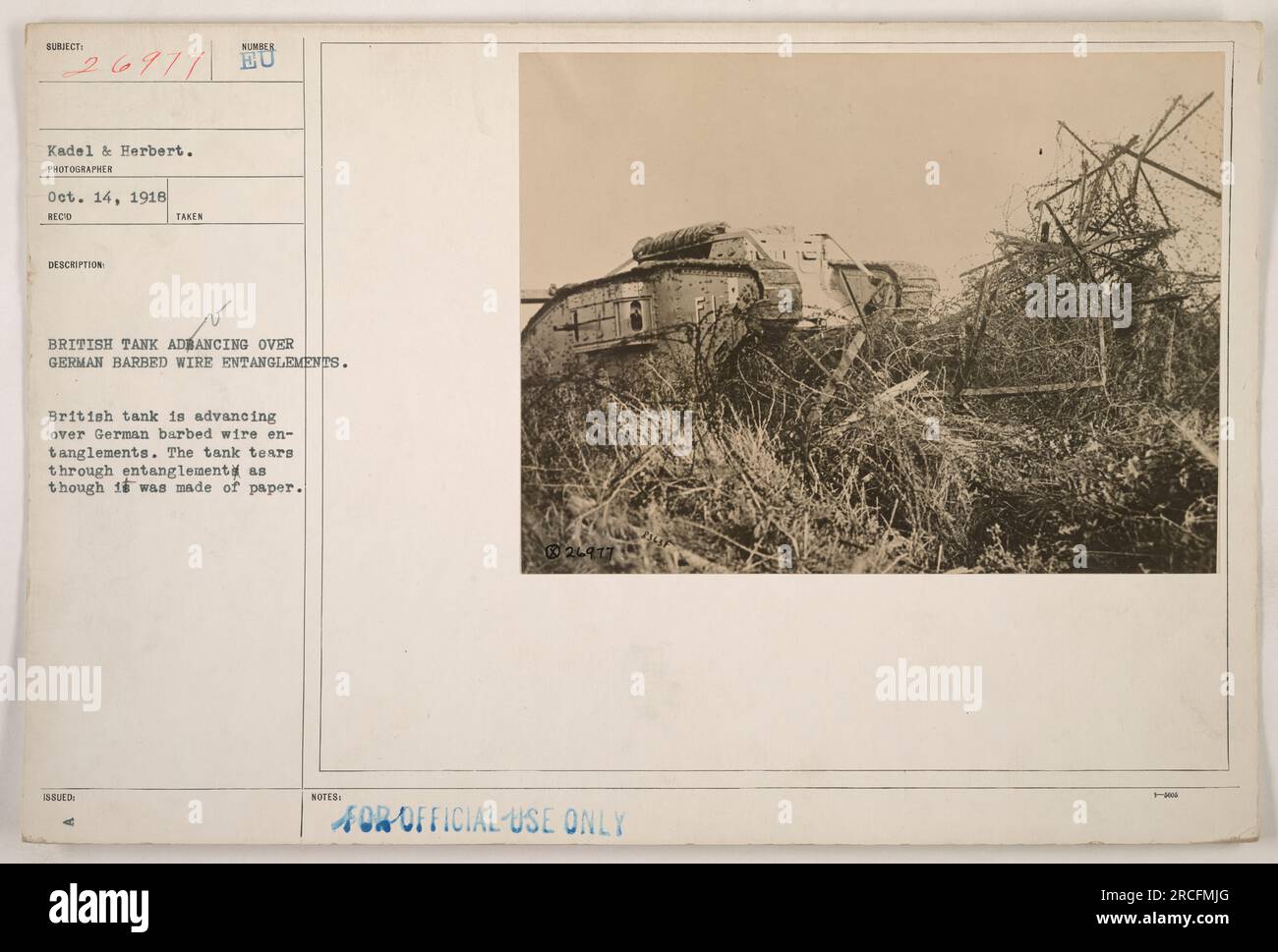 During World War I, this photograph captured a British tank advancing over German barbed wire entanglements. The tank effortlessly tore through the wire, providing a visual representation of the power and efficiency of these military vehicles. This image was taken on October 14, 1918, and was issued to document American military activities. Stock Photo