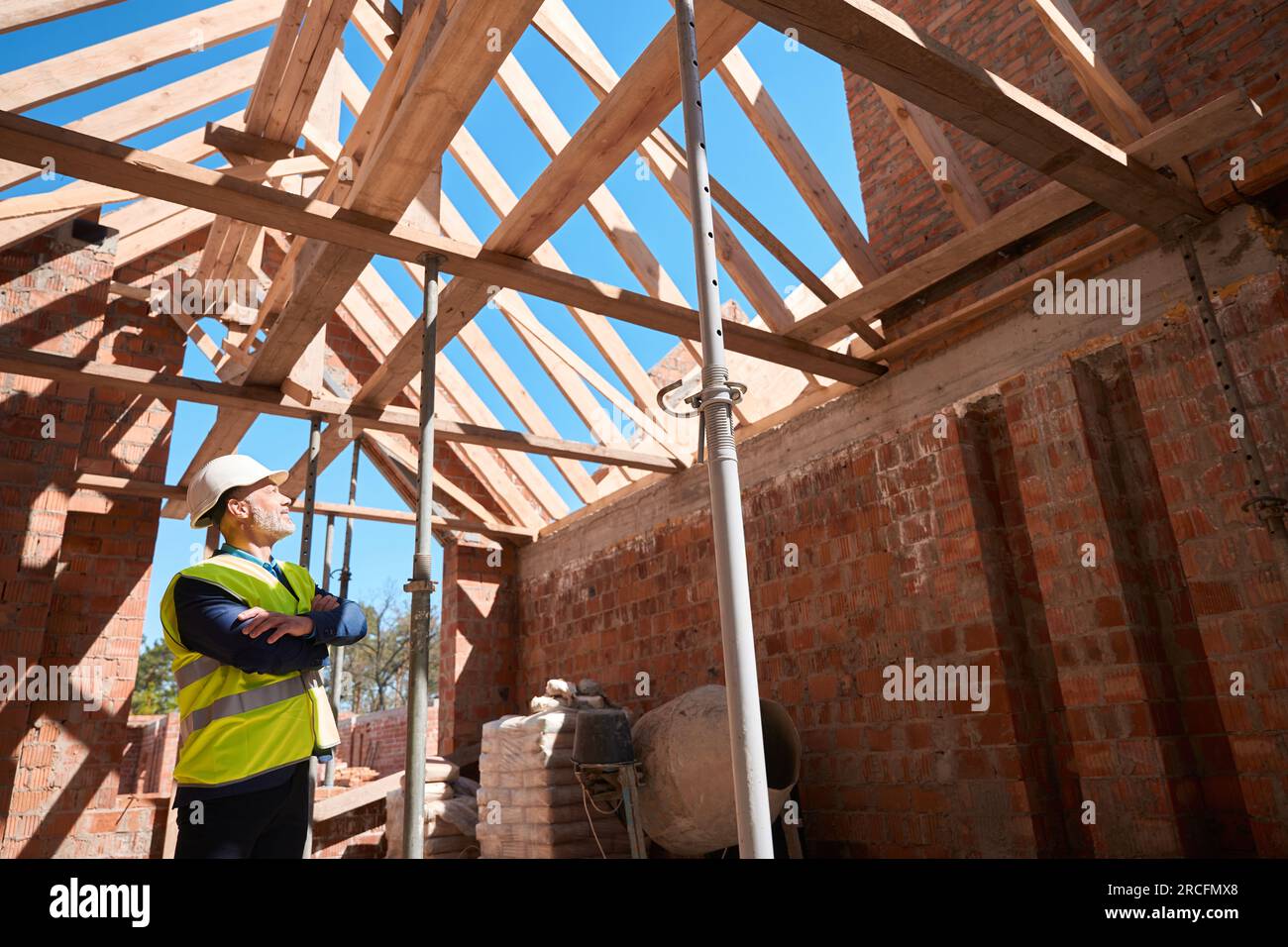 Male constructor in uniform checking walls support and roof beams of ...