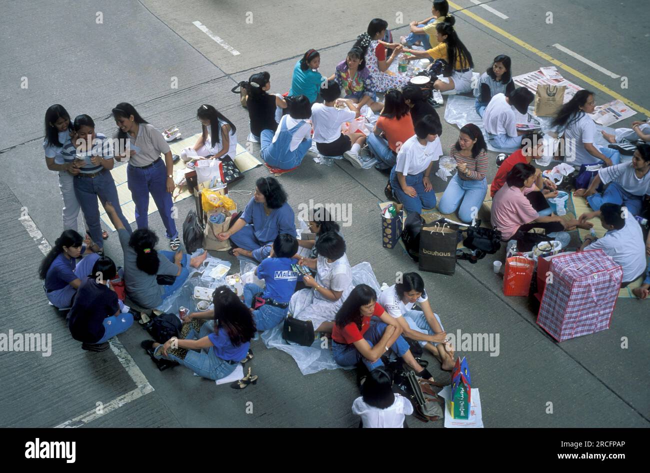 Working and migrants women from the Philippines meet on a sunday on a closed road in the city of Hongkong in Hongkong.  China, Hongkong, October, 1996 Stock Photo