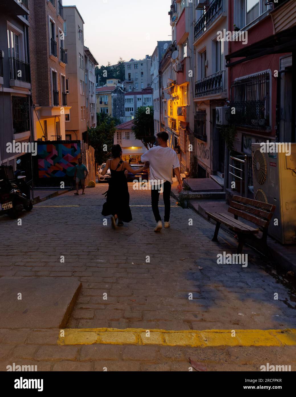 Young couple walk arm in arm on a summers night in the Cihangir neighbourhood of Istanbul, Turkey Stock Photo