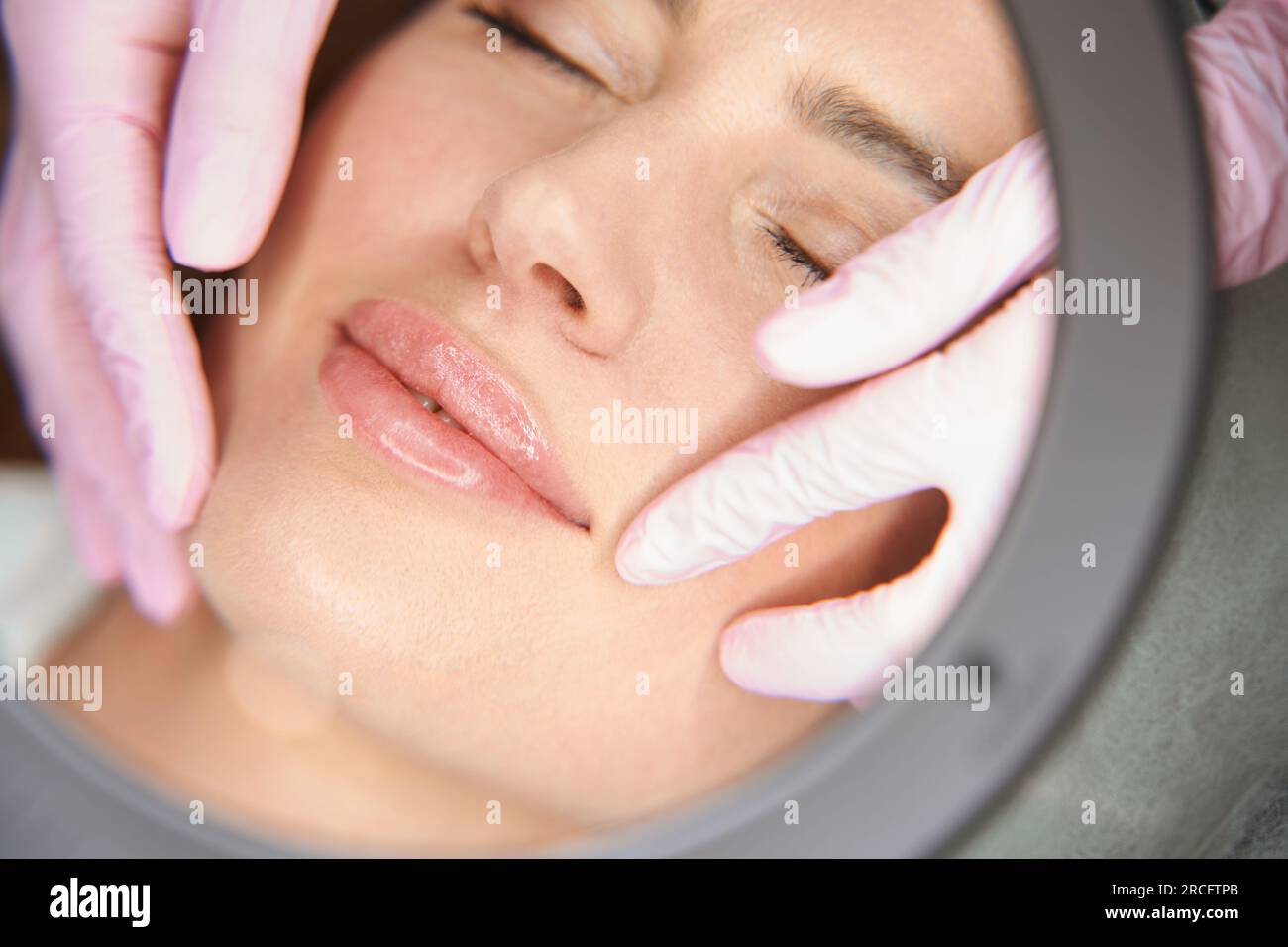 Beautician examines the nasolabial folds of patient after beauty injections Stock Photo