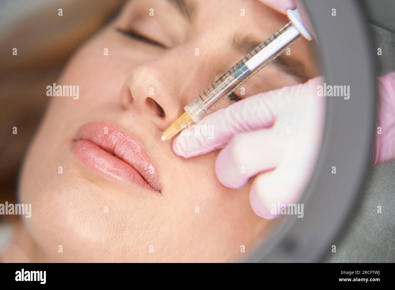 Esthetician makes injections to the woman in the nasolabial fold Stock Photo