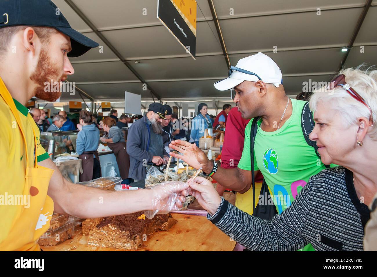 August 11, 2019. Istra, Moscow region. A farmer sells products made with his own hands. Customers are trying products. Fair of cheeses and farm produc Stock Photo