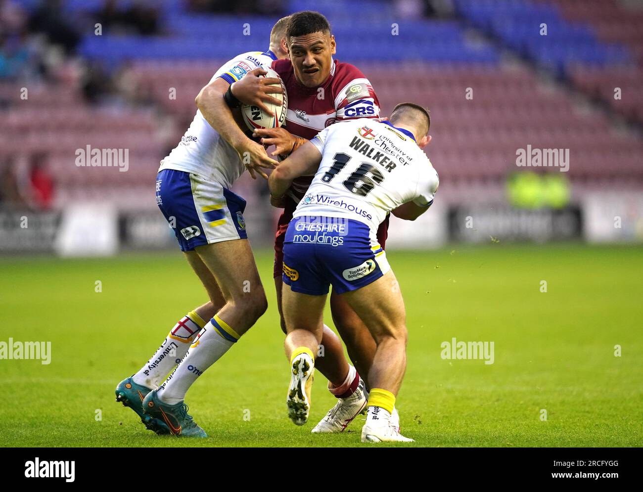 Wigan Warriors' Patrick Mago (centre) is tackled by Warrington Wolves' James Harrison (left) and Danny Walker during the Betfred Super League match at the DW Stadium, Wigan. Picture date: Friday July 14, 2023. Stock Photo