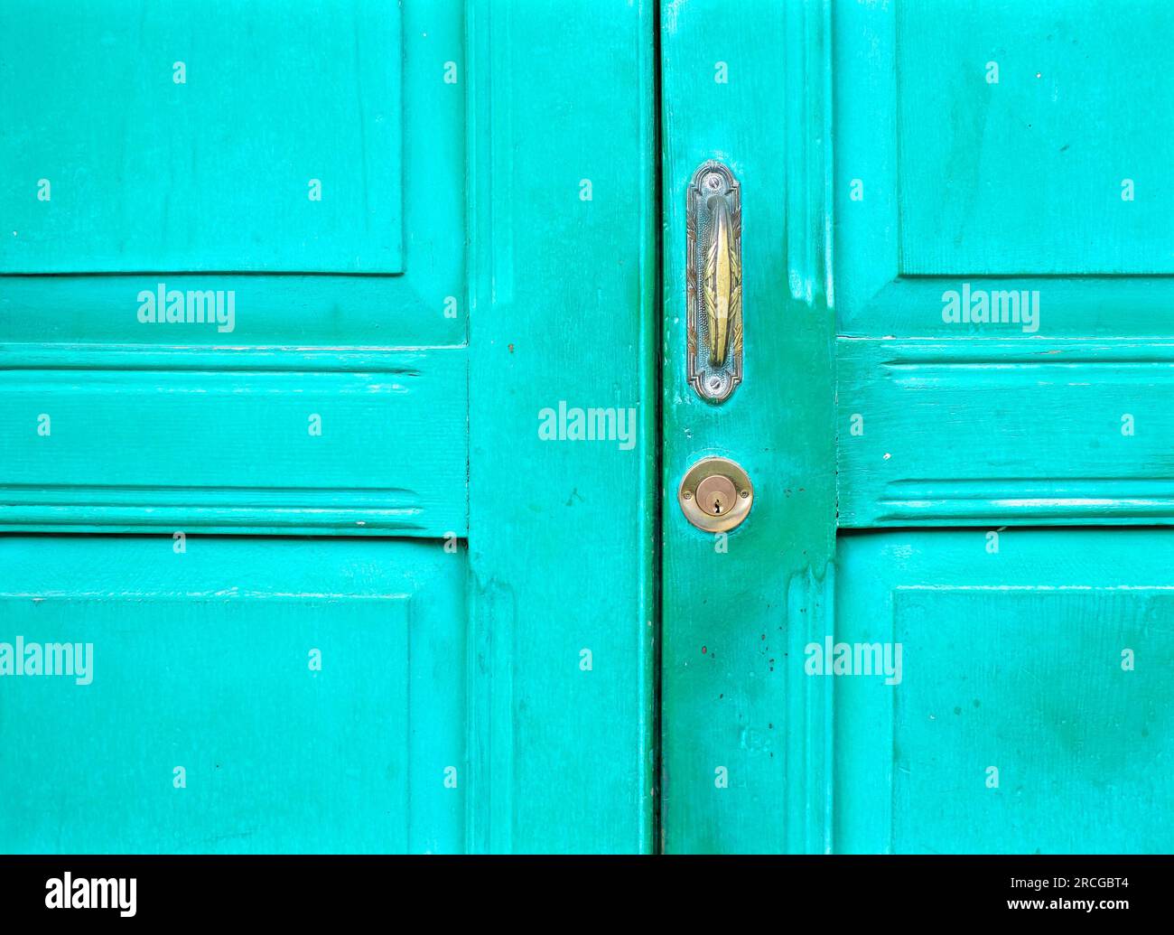 Old worn emerald green door with lock and handle. Stock Photo