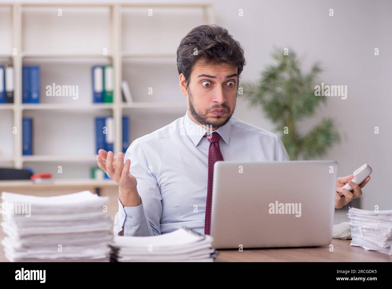 Young employee and too much work at workplace Stock Photo - Alamy