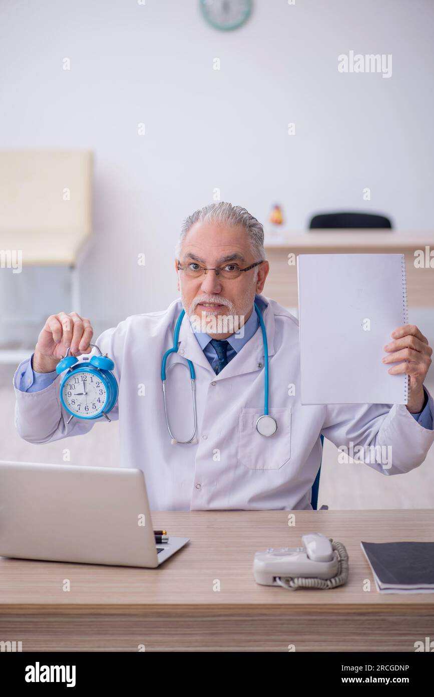 Old doctor in time management concept Stock Photo