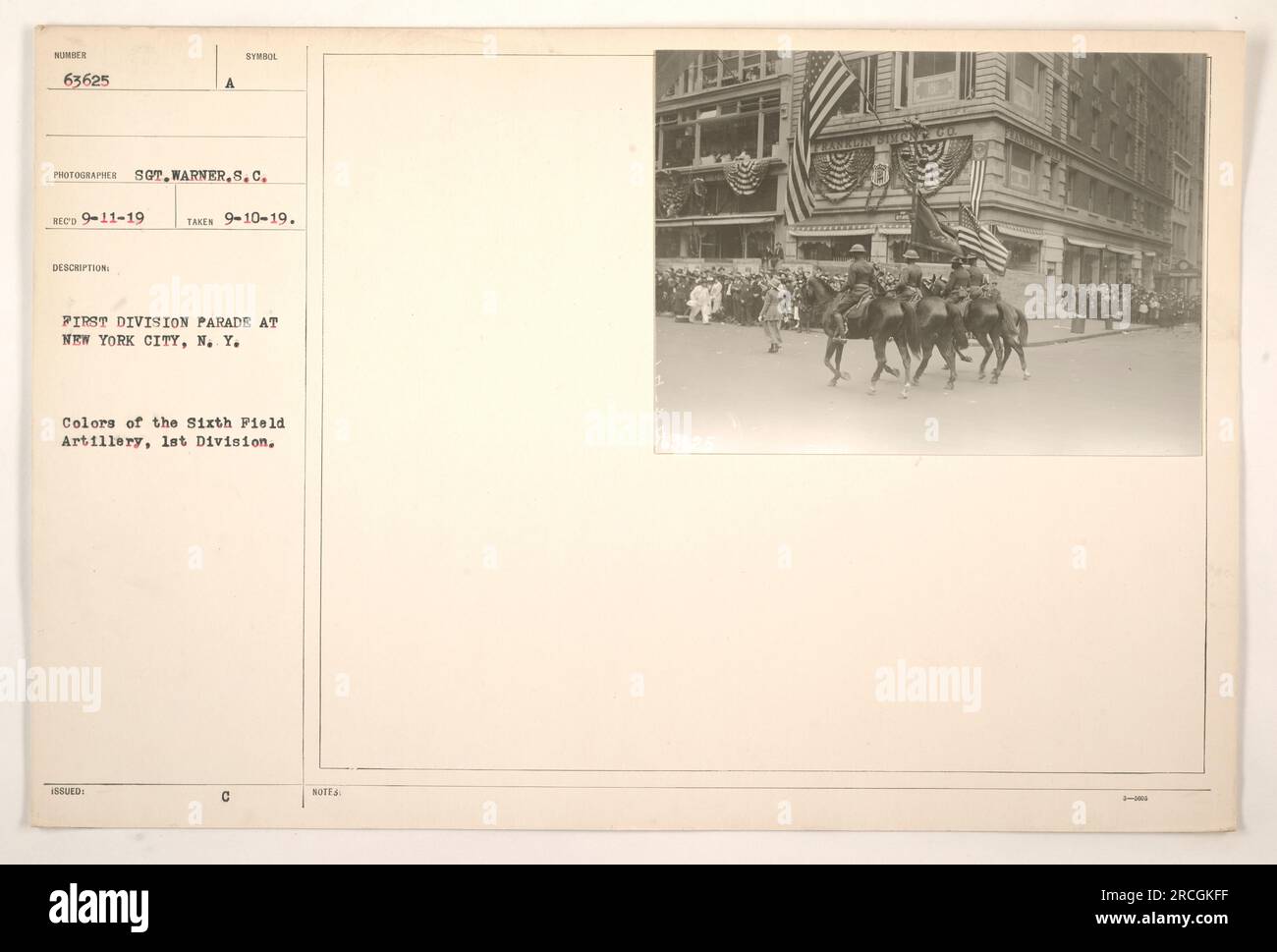 A parade in New York City showcasing the First Division's Sixth Field Artillery during World War One. The soldiers are seen marching in their colorful uniforms while holding their symbolic flags. The photograph was taken by Sot.Warner.S.C. and received on September 11, 1919. The picture was issued under the number 63625 and has the annotation 'Takes 9-10-19'. 3625-NOWY GO. Stock Photo