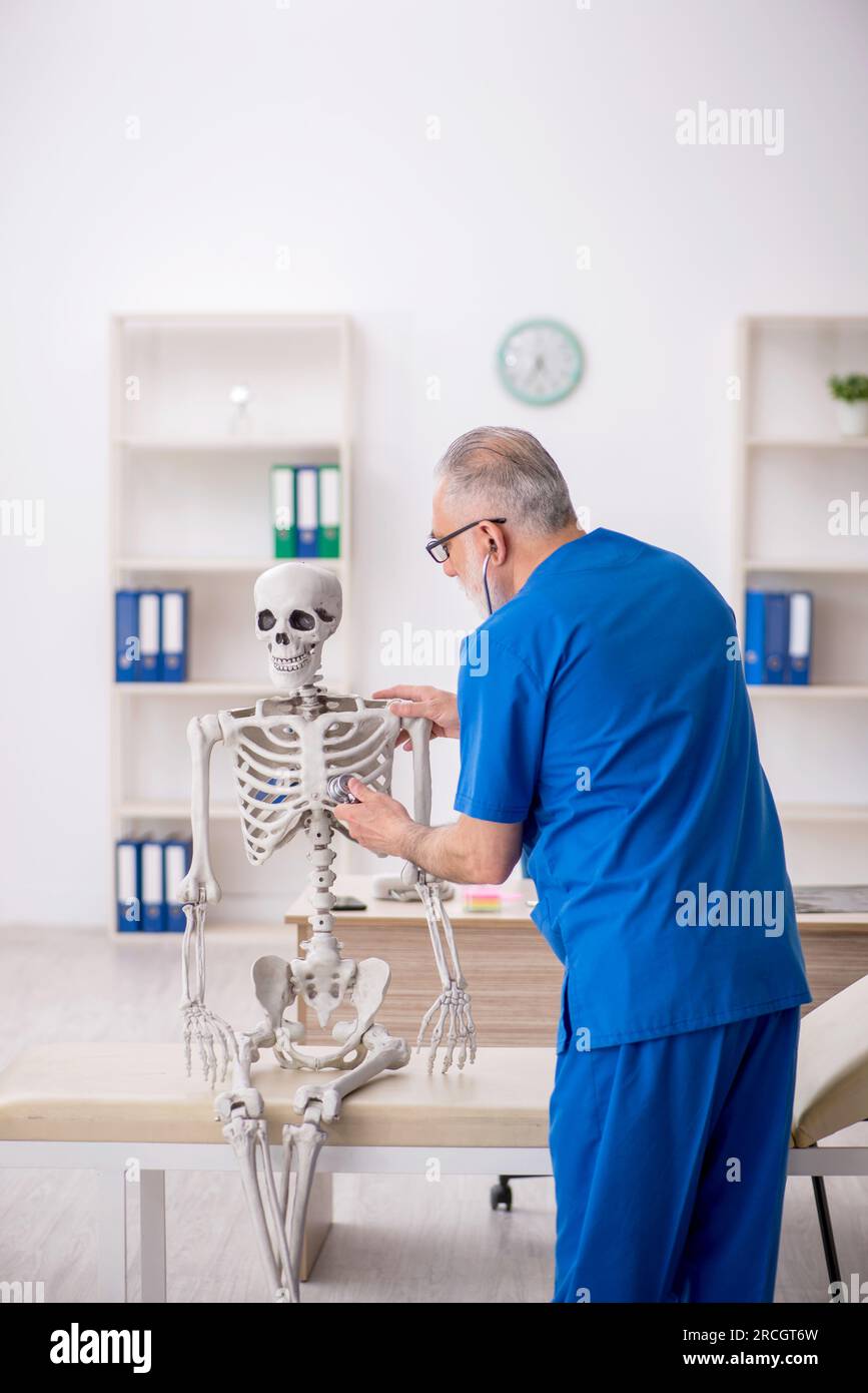 Old doctor examining skeleton at the hospital Stock Photo