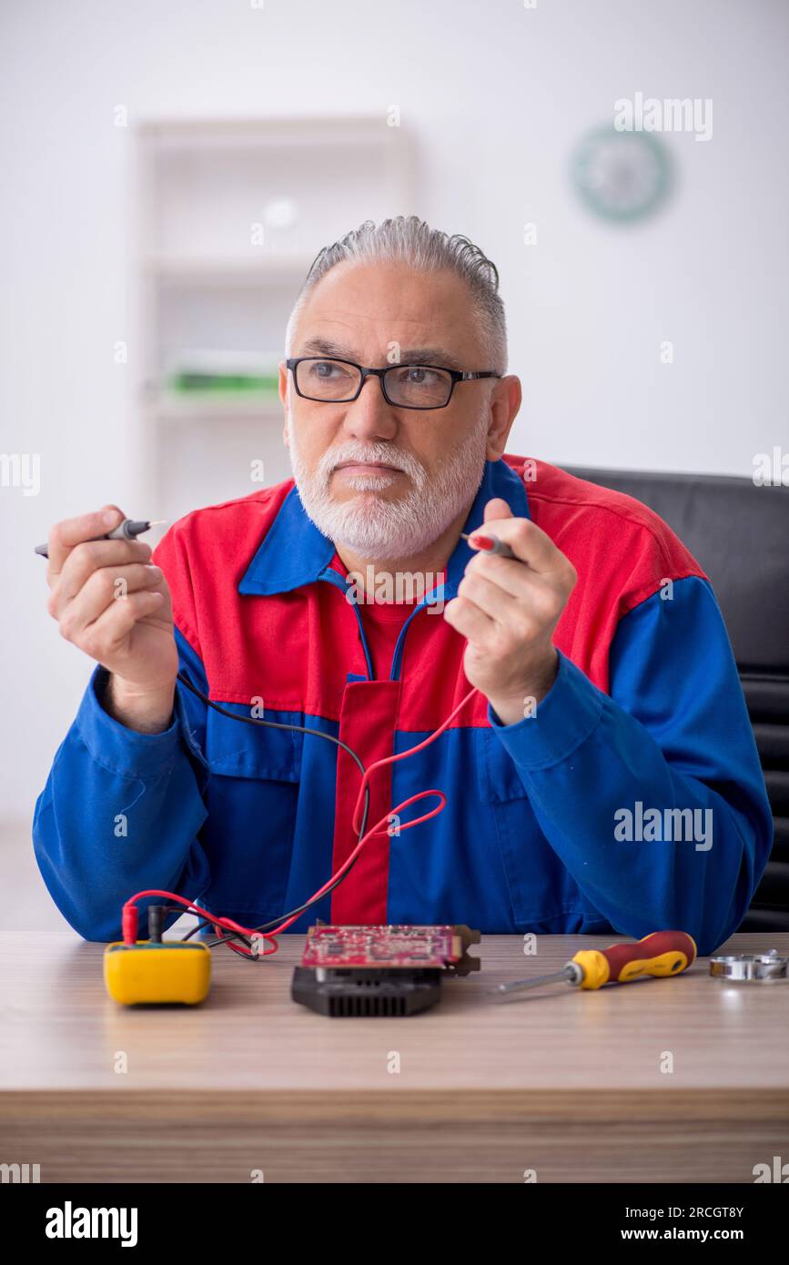 Old repairman repairing computer at the lab Stock Photo