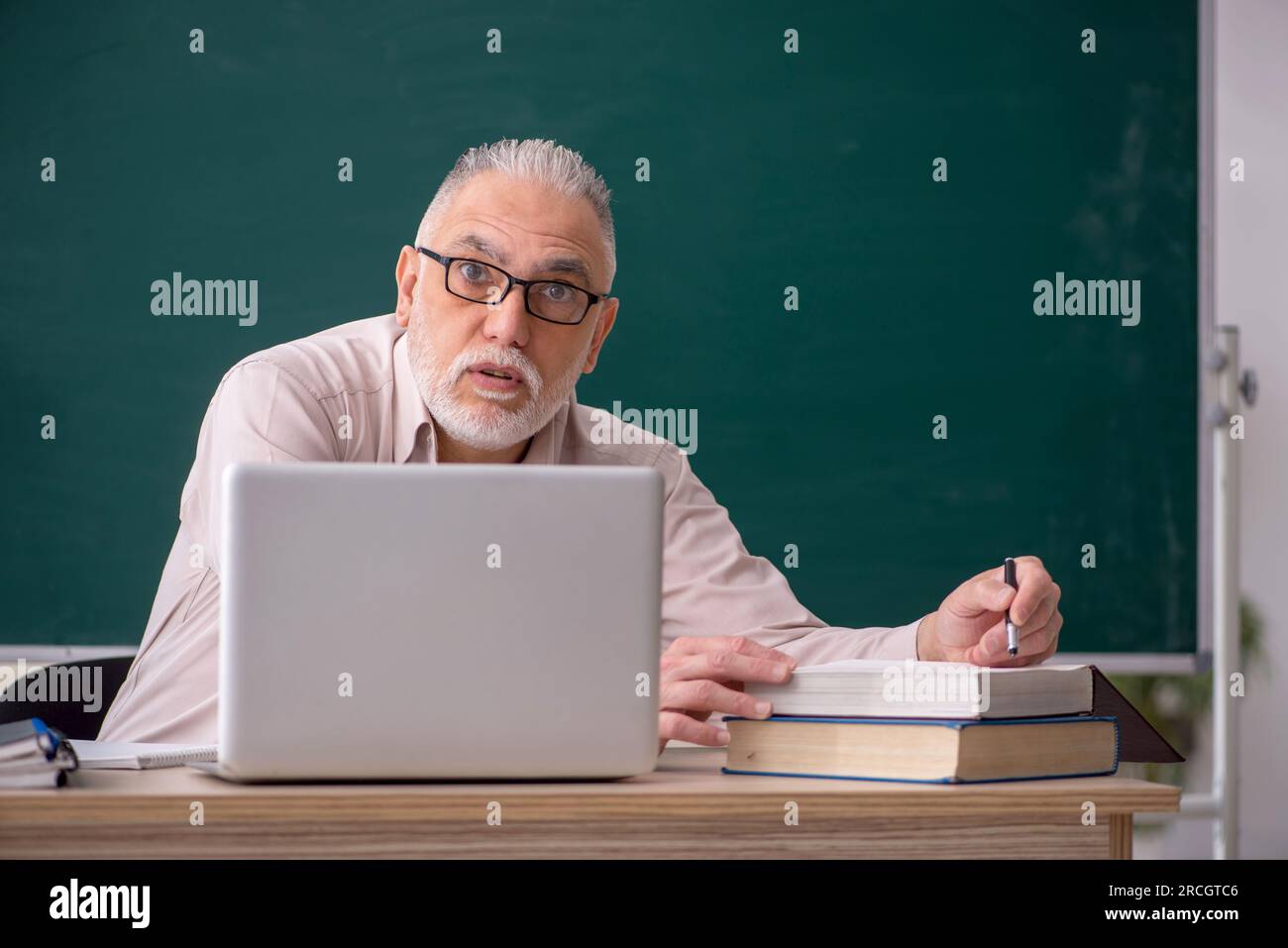 Old teacher sitting in the classroom Stock Photo