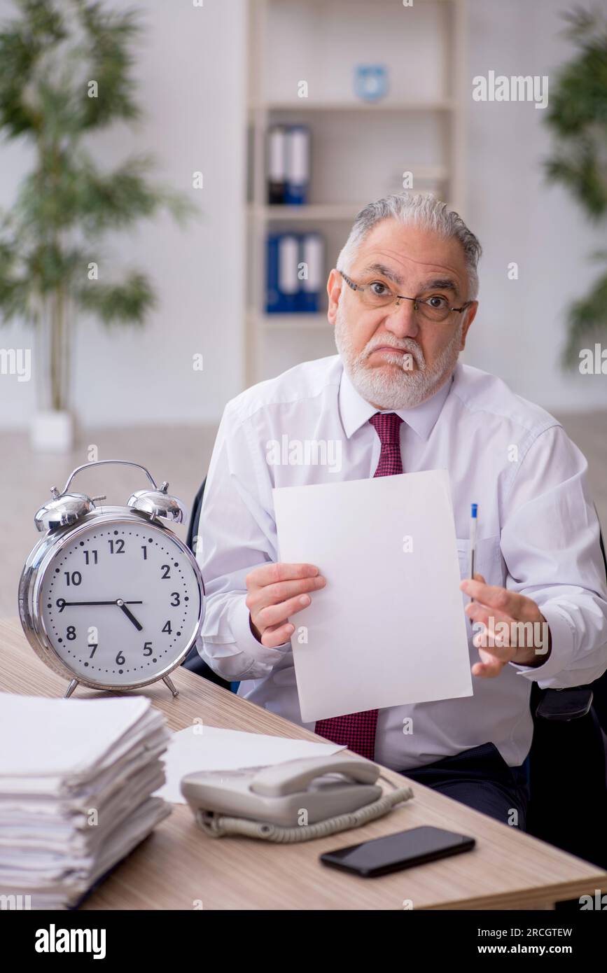 Old employee in time management concept Stock Photo