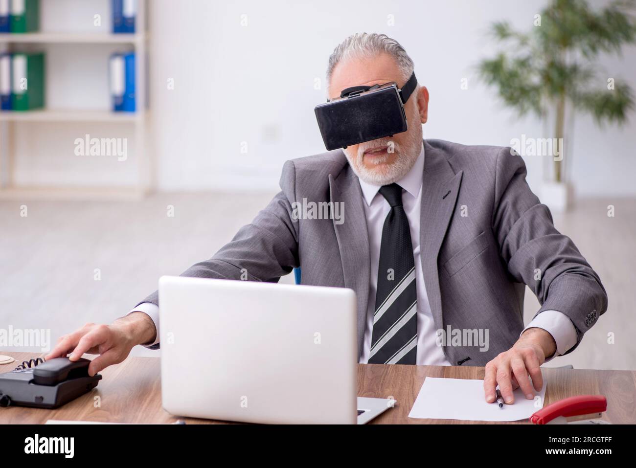 Old employee enjoying virtual glasses at workplace Stock Photo